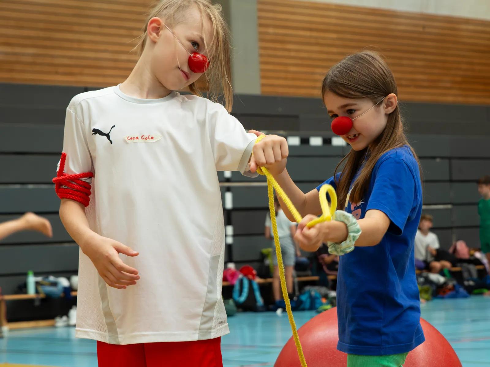 Trainer hilft einem Kind beim Schwingen an einem Seil in der Sporthalle