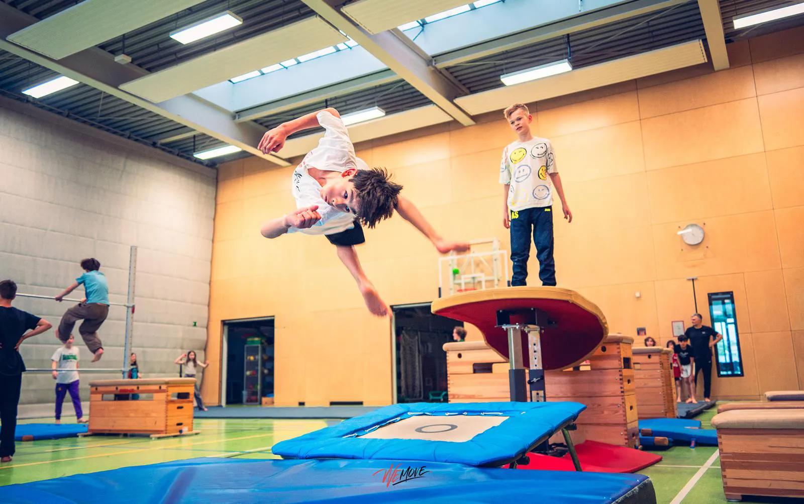 Mehrere Athleten springen gemeinsam in einer Sporthalle
