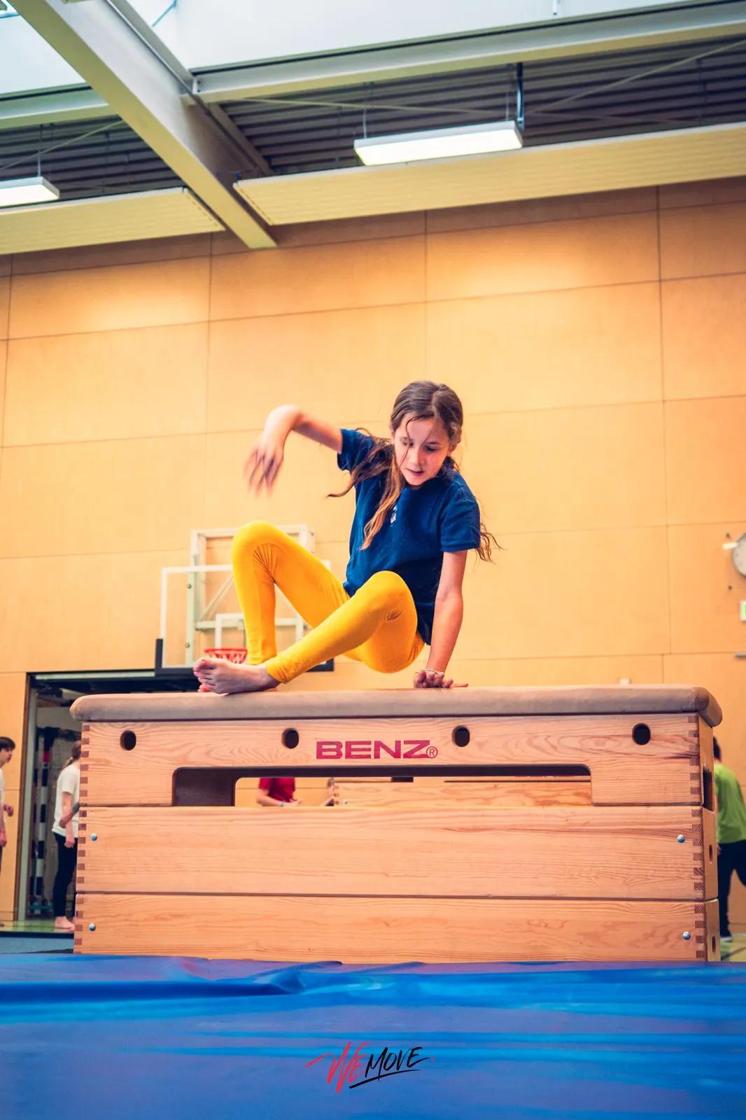 Kind springt auf einem Trampolin, im Hintergrund die Halle